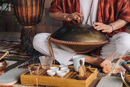 在茶叶仪式期间 用猎户座舌鼓敲响一个演奏现代乐器的人的手贴近韵律活力音乐振动游戏语言精神谐振艺术品雕塑图片