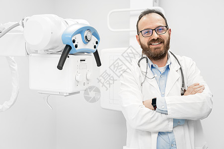 站在X光设备旁边的有自信的放射学家微笑男性医院x射线成人病人职业扫描器科学诊所实验室图片