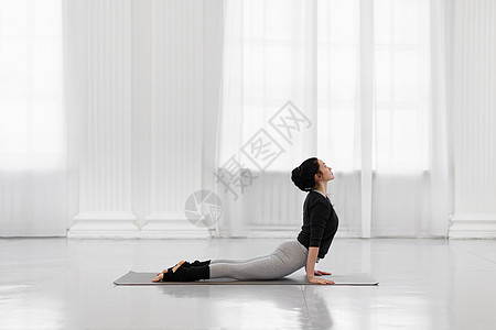 美丽的年轻女性在瑜伽工作室的灰色垫子上做瑜伽姿势冥想女士房间福利平衡成人娱乐窗户身体训练图片