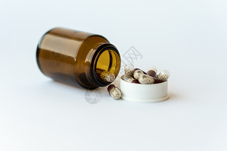医学和药丸 在白色背景特写镜头的药物 有里面胶囊的棕色玻璃桶在白色背景 从倒置的罐子里溢出的药丸落在白色的表面上制药疼痛疾病治疗图片