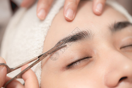 在温泉美容院修剪眉毛服务 脸部理发和用小剪刀工具为面部美容妇女缝合剪裁剪图片