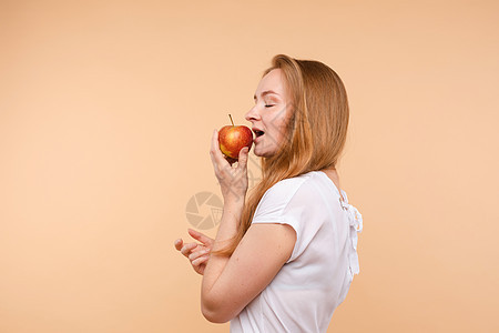 美丽的女孩 绑在后面的头发 吃着美味的苹果女性食物牙齿水果女士快乐小吃维生素幸福微笑图片