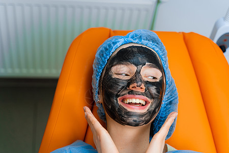 使用外科激光 用黑面罩遮住女孩脸部的碳剥皮 皮肤学和美容学白头色素沉着程序皱纹疙瘩女性病人表皮照片粉刺图片