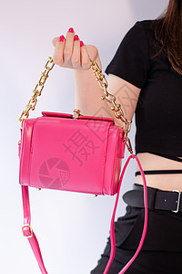 女性手握着一个漂亮的粉红小手提包 产品摄影 时髦的手袋和钱包给女性衣服皮革女士魅力配饰休闲购物粉色销售金子图片