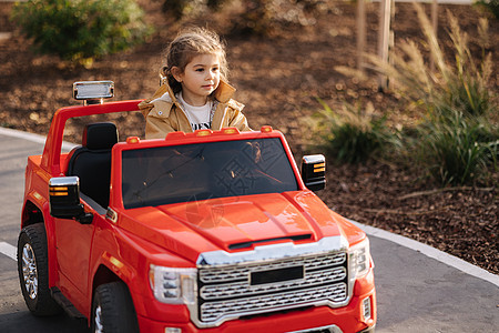 可爱的小女孩骑着一辆红色的电动吉普车在迷你城市中行驶 玩具城的萌娃小路 为娱乐而玩乐趣活动喜悦快乐绘画运动公园驾驶校园男生图片
