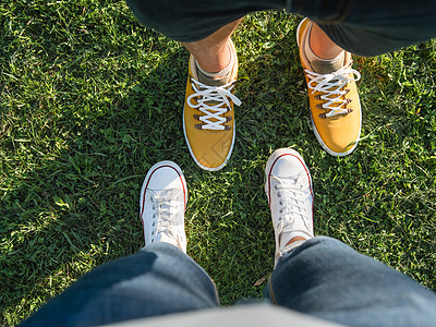 男男女女站在公园绿草坪上 一对夫妇在约会 对现代嬉皮士运动鞋的高视线 城市时尚夫妻黄色女士草地花园潮人绿色图片