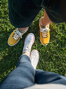 男男女女站在公园绿草坪上 一对夫妇在约会 对现代嬉皮士运动鞋的高视线 城市时尚花园夫妻潮人黄色绿色女士草地图片