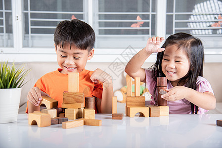 男童和女童玩木制建筑工木块建筑的游戏生活教育乐趣孩子们桌子幼儿园活动房间闲暇立方体图片