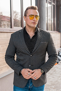 时尚的年轻小伙子肖像 在露天街上穿着灰色夹克和墨镜黑衬衫的欧洲外观商务人士成人商务潮人太阳镜男性衣服手提包城市眼镜西装图片