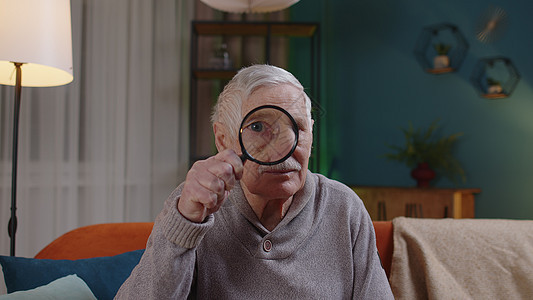 高祖父男子透过放大镜 阅读 研究 在家检查等 寻找资料和资料背景图片