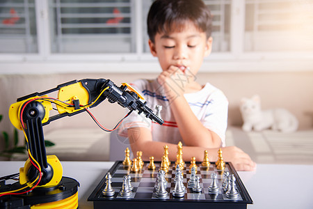 亚洲小男孩思考和等待机器人臂象棋游戏的亚洲男孩科学学习助手作坊金属幼儿园孩子桌子男生手臂图片