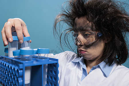 疯狂的科学家 带着肮脏的脸和乱七八糟的头发 在实验室化学爆炸后分析塑料试瓶图片