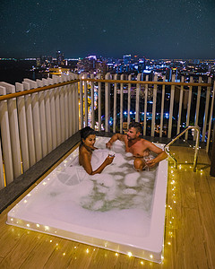 一对男女在浴缸的阳台上眺望泰国芭堤雅的海湾 男人和女人在按摩浴缸中奢华洗澡男朋友周年微笑纪念日水池热情房间假期图片