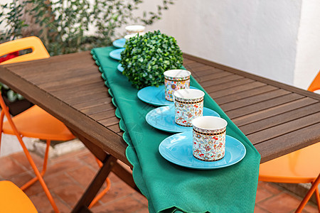 后院配有杯子和盘子的木桌图片
