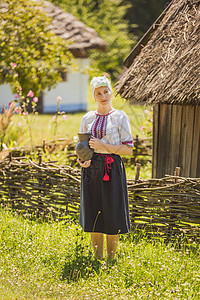 妇女穿着乌克兰民族服装 手里拿着一壶酒图片