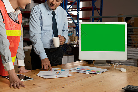 导游团在仓库储藏室内显示绿色屏幕的计算机 Name监视器工厂笔记本互联网店铺运输货运托盘工作展示背景
