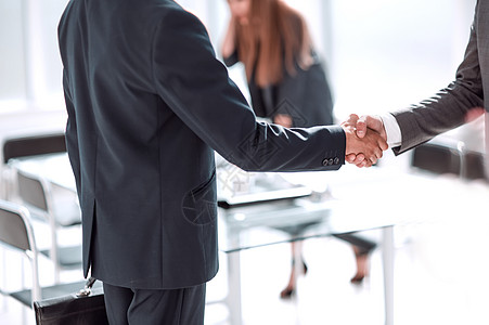 办公室背景中商界人士的握手之握手讨论生意推介会管理人员组织互动合作职场商务合伙图片