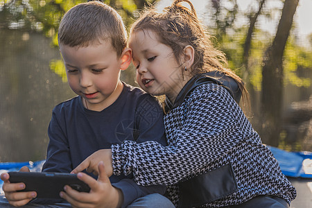 孩子们看着电话看手臂家庭手机手表电讯系统孩子说话娱乐互联网图片