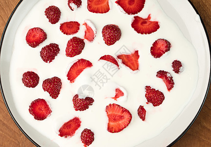 美味多汁的红草莓被埋在奶制品酸奶油中 在木板上的白色盘子里养分甜点季节宏观浆果叶子水果美食团体食物图片