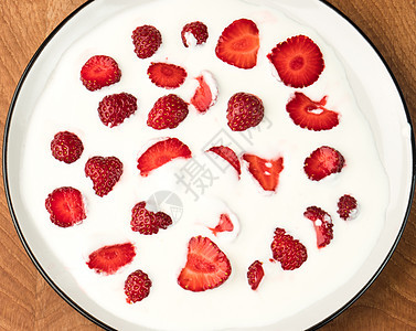 美味多汁的红草莓被埋在奶制品酸奶油中 在木板上的白色盘子里营养美食食物饮食水果甜点叶子团体浆果养分图片