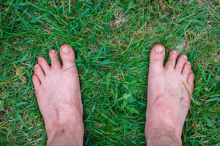 人类赤脚站在新鲜绿草上图片