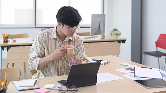 忙碌的年轻商务人士喝咖啡和检查电脑平板电脑上的金融信息 (笑声)图片