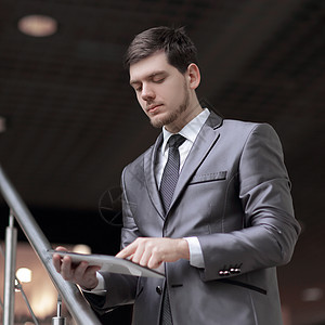 在办公大楼使用平板电脑站立在台阶上的英俊商务人士走廊高清图片素材