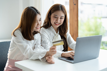 两个亚洲女友在网上购物 家里用智能电话和信用卡买手机和信用卡键盘笔记本电脑银行技术购物女士销售支付商业图片