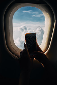 飞机照片年轻女子在飞机飞行期间从飞机窗口拍摄照片时观看了画面 这名少女是一名女青年背景