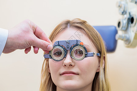 一名男性观察家检查一个年轻女孩的视力和试镜框架验光验光师玻璃仪器病人女士男人诊所医生药品图片