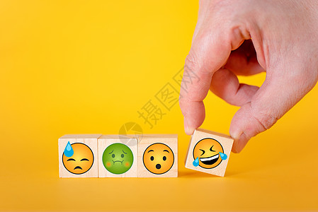 黄色背景的Emoji表情 手拿一个带笑容的立方体技术全球情绪网络符号社会社论微笑服务图片