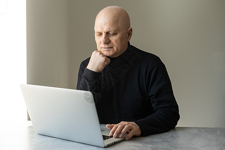 穿着聪明随意风格的英俊老男人正在用笔记本电脑商业工作沙发工具老年男人商务建筑师网络眼镜图片