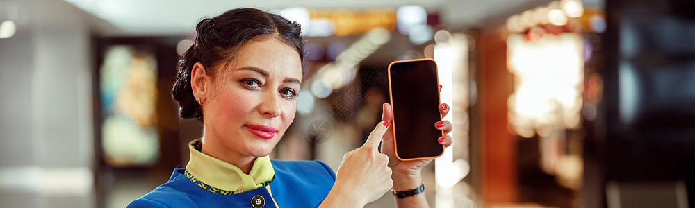 女空勤人员指着机场智能手机的女乘务员旅行工具国际服务员展示飞机女士触摸屏航空公司航班图片