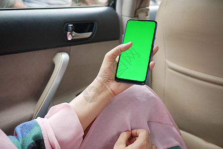 妇女手持智能手机 用绿色屏幕在汽车中图片