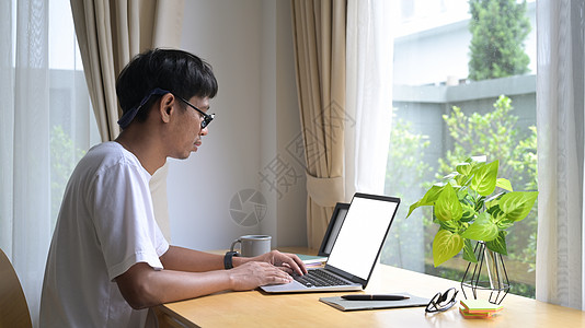 观看坐在舒适的客厅和笔记本电脑上浏览互联网的侧边年青人图片