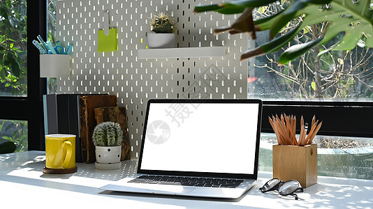 现代工作区配有笔记本电脑 咖啡杯和白色桌子上的用品 家庭办公室工作场所概念图片
