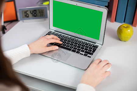 手托电脑绿屏 键盘上的女孩用左手打字 用右手操作鼠标 (笑声)背景