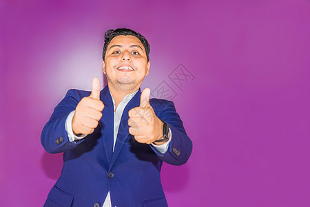 穿蓝色西装的拉丁男人 用纯紫背景举起两手拇指背景图片