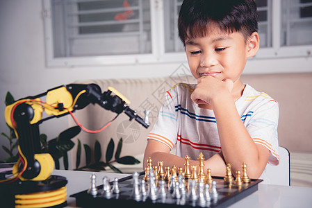 亚洲小男孩思考和等待机器人臂象棋游戏的亚洲男孩男生课堂幼儿园机器人孩子作坊助手学校工程科学图片