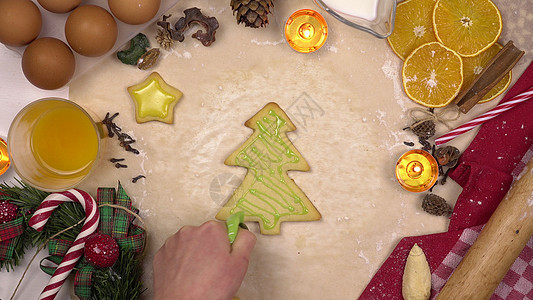 一位年轻女性装饰圣诞喜庆曲奇饼 以圣诞树的形式 配有彩色冰淇淋 从上面查看雪人面包木板奶油假期桌子甜点庆典食物新年图片
