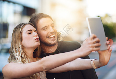 一对快乐的年轻夫妇在数字平板电脑上拍自拍的肖像 简直就是一对美人儿图片