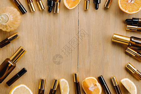瓶子和柠檬中的必要油 木质表面的橙子芳香药品滴管液体血清身体化妆品水果木头写作图片