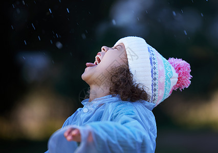 每个人都试图用嘴接住雨滴 一个可爱的小女孩独自站在外面在雨中玩耍的镜头图片