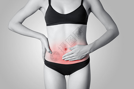 在灰色背景下 对胃痛或消化或周期性循环的年轻妇女进行近视治疗躯干压力药品腰围疾病女士按摩经期病人图片