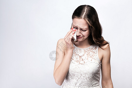 带着雀斑和白裙子的哭泣女人 以及银灰色背景的聪明手表 复制空间图片