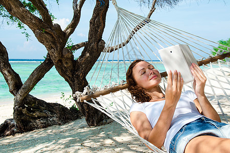 坐在吊床上的女人 在海滩上拿着笔记本电脑图片