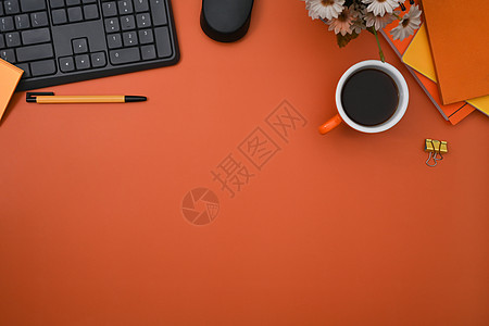顶尖的时尚工作空间 有无线键盘 咖啡杯和橙色背景的笔记本图片