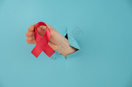 女人用红弓棍从蓝色背景的洞里伸出来 这是防治艾滋病的象征 笑声免疫结核医生药品援助考试中风捐款国家棕榈图片