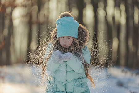 女孩吹在雪上 她的手套上的雪耀斑公园一个男孩假期幸福乐趣童年享受背景青少年图片