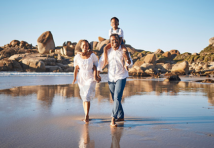 年轻的非洲裔美国父母手牵着手 带着他们的两个孩子 沿着海滩散步的全长肖像 有小女儿和儿子的年轻家庭共度时光 享受假期父亲孩子们女图片